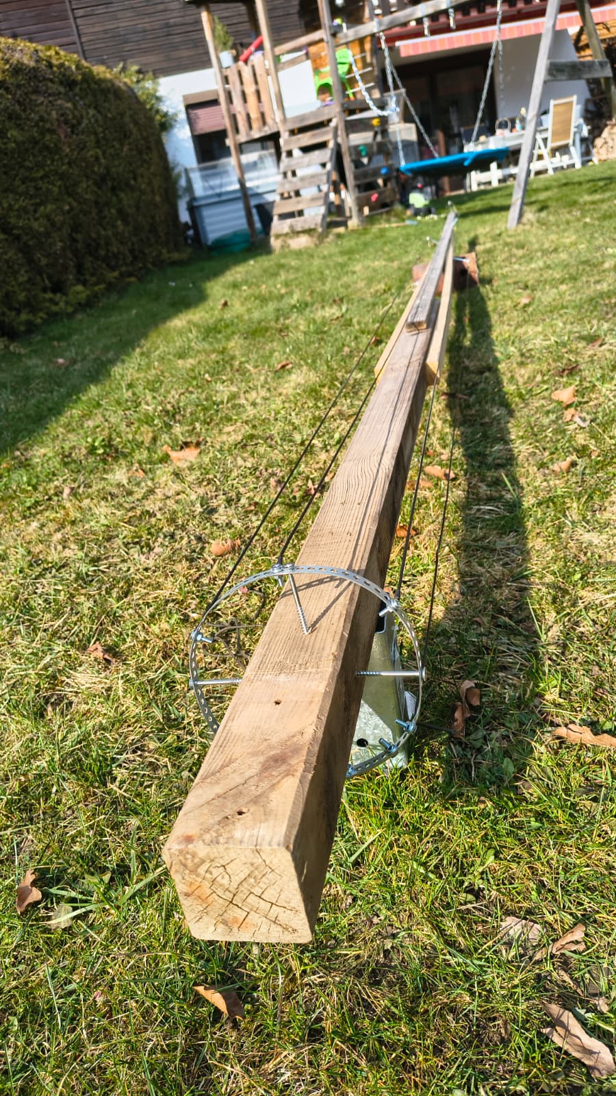 Der Lattenmast liegend am Boden mit sichtbarem Edelstahl-Speisering und Drahtseilklemmen