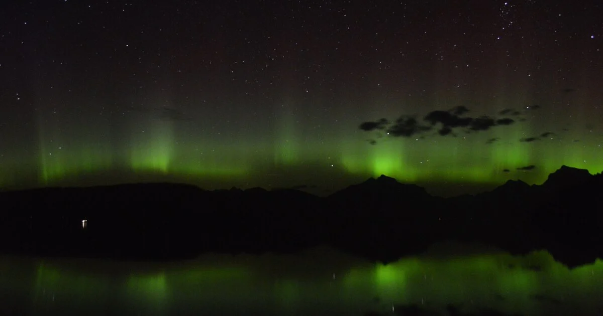 Grünes Polarlicht über einer nächtlichen Landschaft
