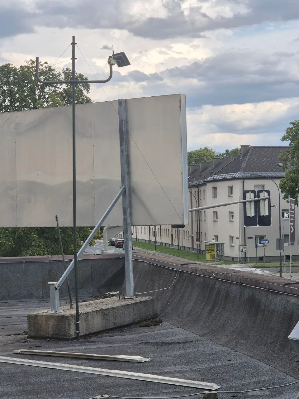 Abgespannter Antennenmast mit Solar-Node auf einem Flachdach in Villach, dahinter Wohnhäuser