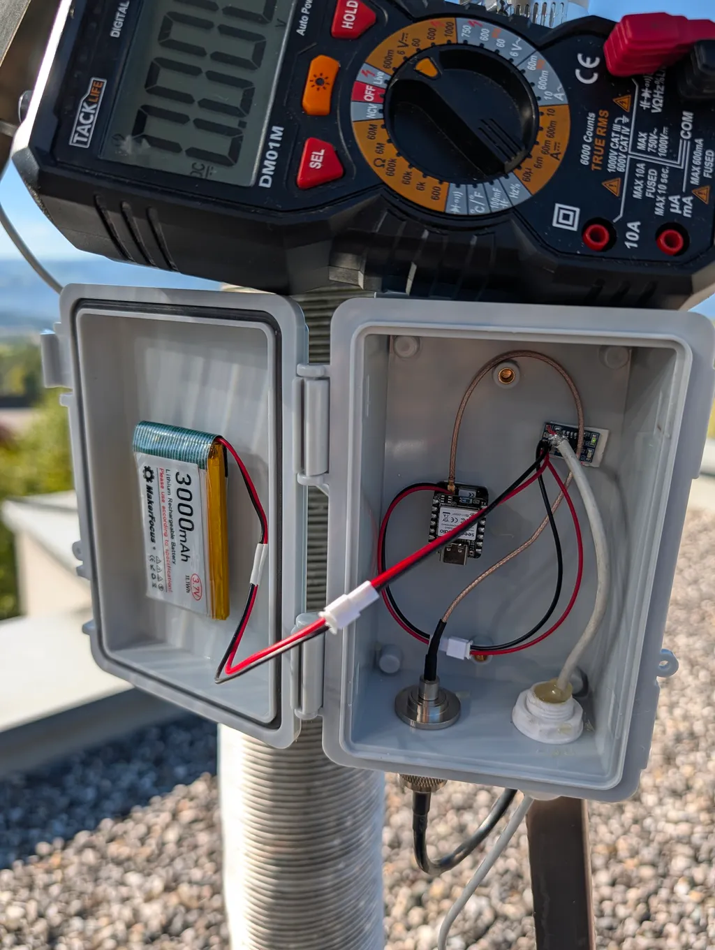 Geöffnetes Gehäuse mit XIAO-Board, 3000-mAh-Akku und Multimeter beim Messen