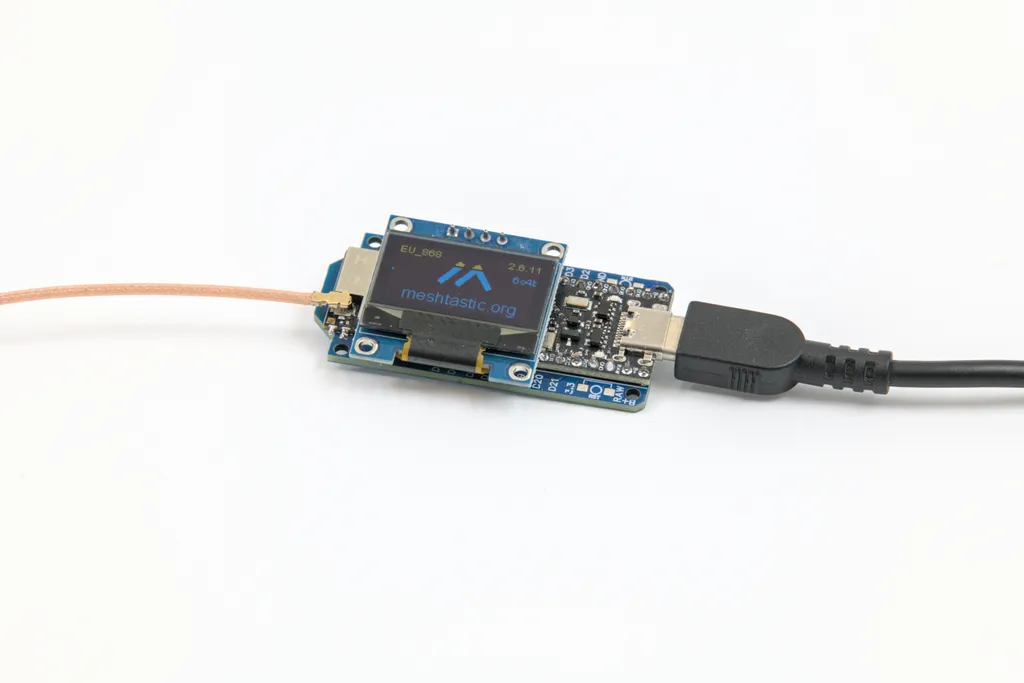 Kleiner Meshtastic-Node mit OLED-Display, das die Region EU_868 und die Firmware-Version anzeigt, mit angeschlossener Antennenleitung