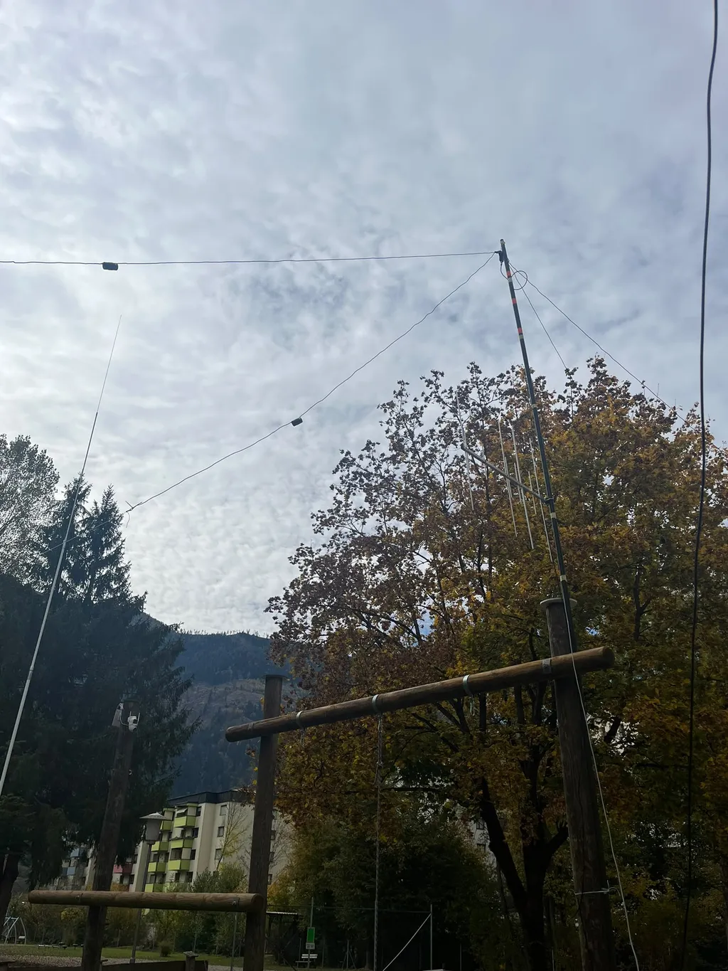 Yagi-Antenne am Mast, davor ein Dipol mit Traps und im Hintergrund eine Vertikal vor Herbstlaub und Bergen