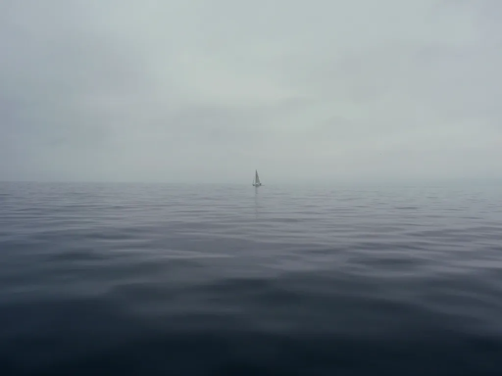 Einzelne Segelyacht auf ruhiger, diesiger See ohne Land in Sicht